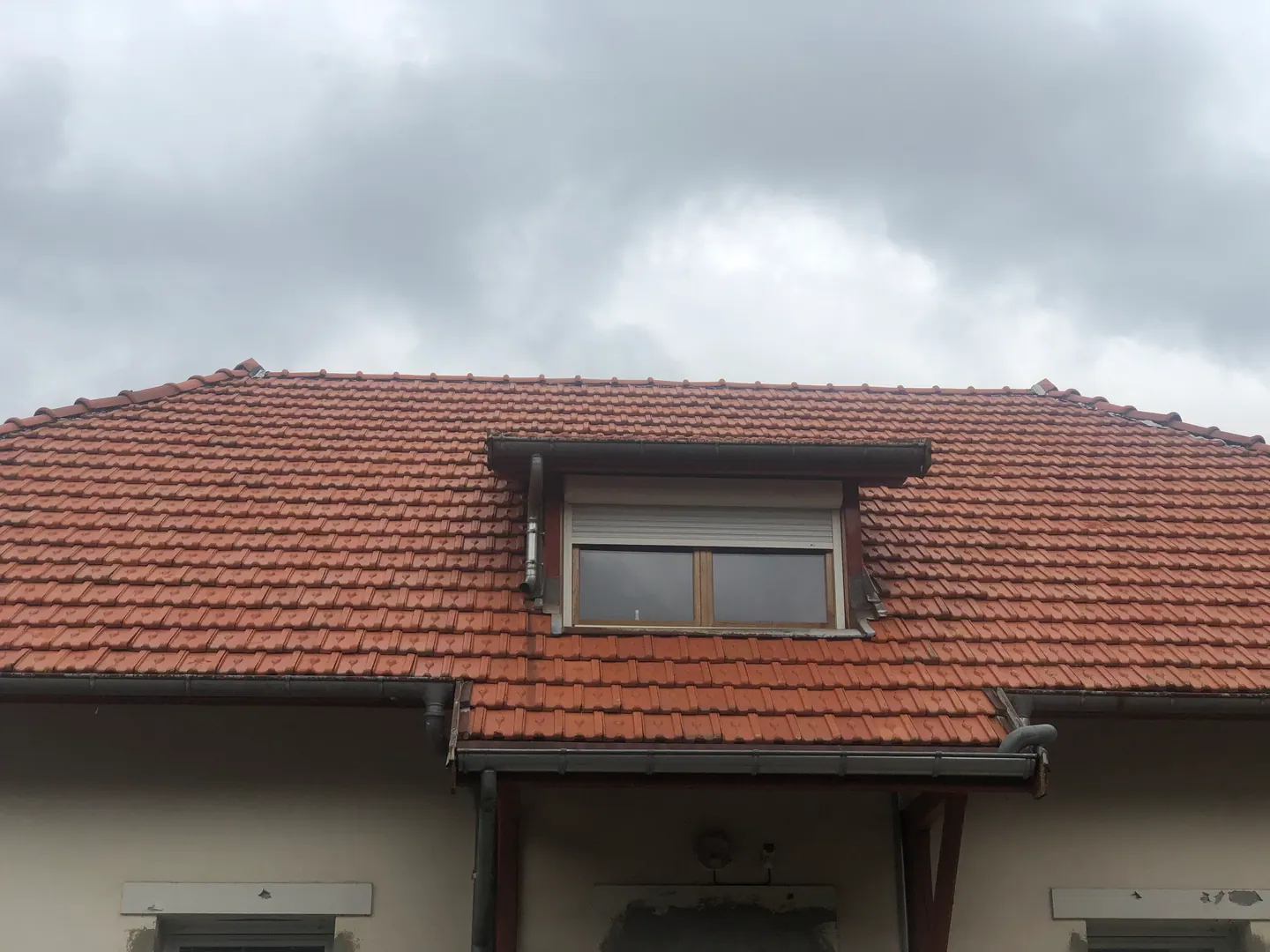 Toiture en tuiles rouges avec lucarne et gouttière